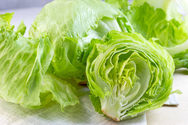 salada de alface de iceberg verde fresco deixa corte em fundo claro sobre a mesa na cozinha - iceberg lettuce - fotografias e filmes do acervo