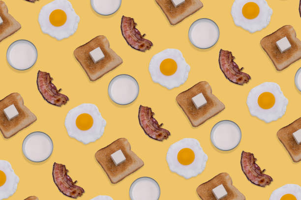 istock Pattern made with fried eggs, slices of crispy bacon, toast bread with butter and glasses of milk on pastel yellow background. 1352143028