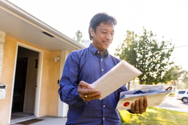 mature filipino person checking the mail at home - looking into mailbox imagens e fotografias de stock