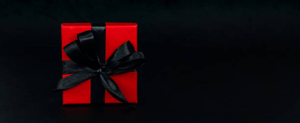 istock Red gift box with black ribbon on black background 1352149692
