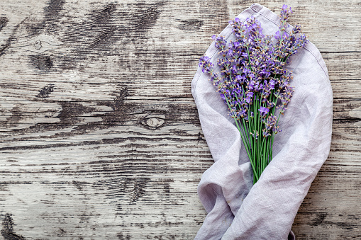 Bouquet of lavender with copy space for text. Fresh lavender flower bouquet on old rustic wooden table on violet fabric. Flatlay purple herbal flower blossom. Lavender aromatherapy