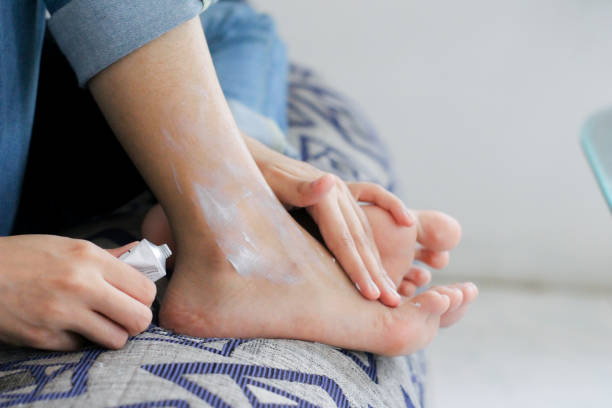 自宅で足元でスキンケアを使用している若い女性 - body care femininity human leg human foot ストックフォトと画像