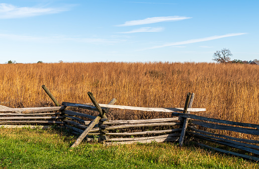 A wooden fence with a wheat field behind it at the Gettysburg National Military Park on a sunny fall day