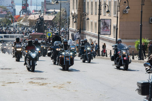 Column of motorcyclists rides along the central street. stock photo