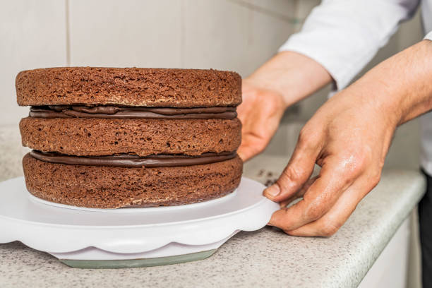 istock Pastry chef placing a chocolate cake on a white tray in a kitchen. 1352160803