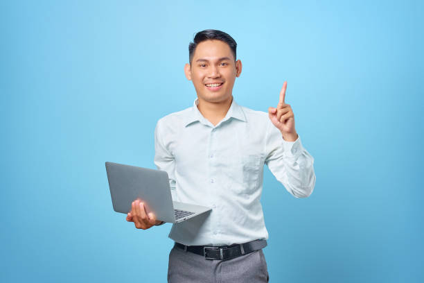 istock Happy young handsome businessman having a creative idea while holding a laptop on blue background 1352164511