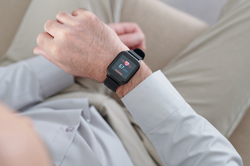 Hands of man looking at screen of smartwatch checking his heart rate