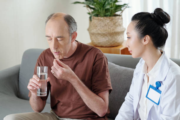 istock Doctor Controlling Man Taking Medicine 1352169012