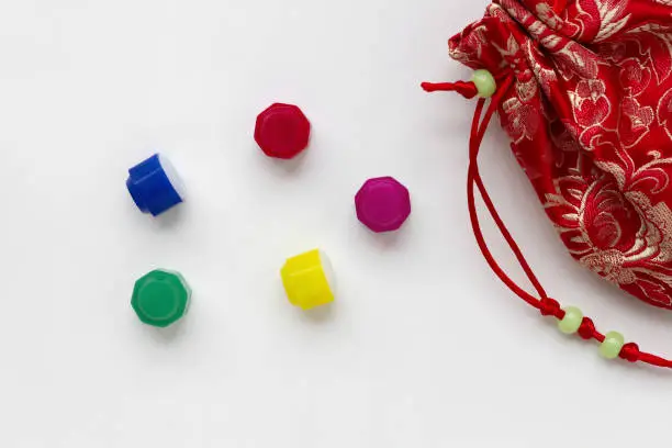 Photo of Korean traditional game kit Gonggi. Colourful plastic stones with coloful pouch isolated on white background.