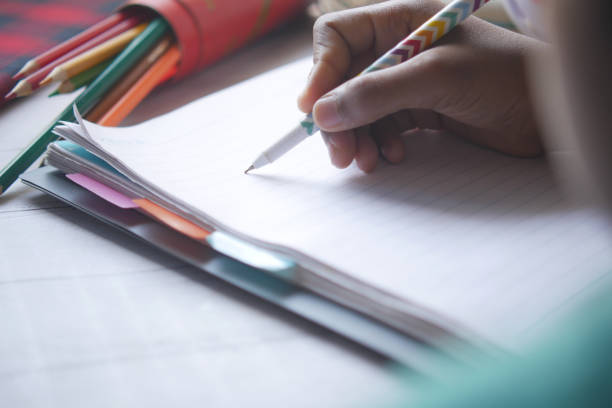 istock rear view of child boy hand writing on notepad. 1352173062