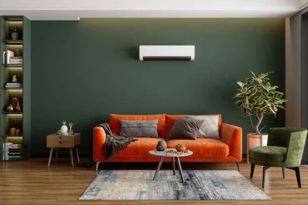 modernes wohnzimmer mit klimaanlage, orangefarbenem sofa und grünem sessel - wohnzimmer stock-fotos und bilder