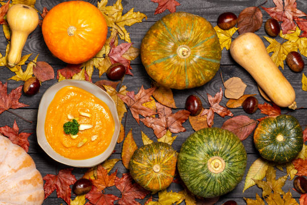 Pumpkin soup garnished with chestnut pieces and parsley on a dark wood background with leaves, pumpkin and chestnuts. Flat Lay with, top view. stock photo