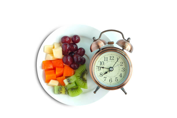 istock Antique clock needles Fruit on isolated white background . Healthy food concept. 1352181727