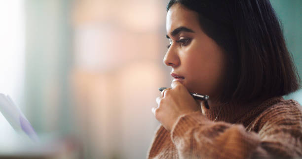 istock Shot of a young woman going through paperwork while studying at home 1352185155
