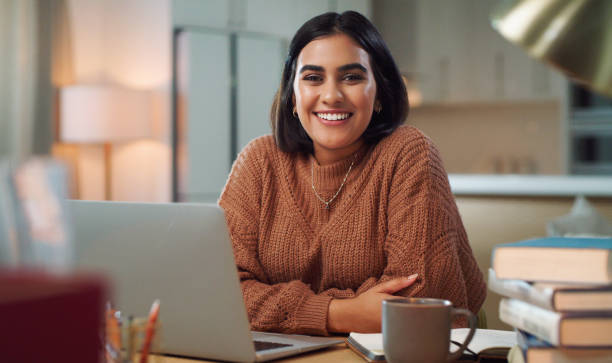 istock Portrait of a young woman using a laptop while studying at home 1352185837