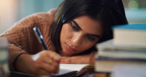 istock Closeup shot of a young woman writing notes while studying at home 1352185850