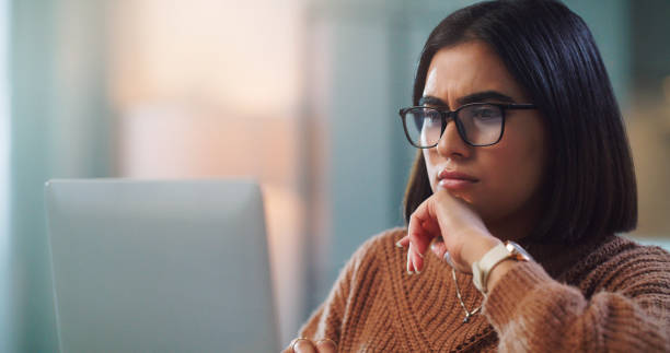 istock Shot of a young woman looking confused while using a laptop to study at home 1352185864