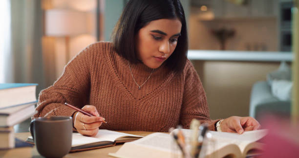 istock Shot of a young woman writing notes while studying at home 1352185876