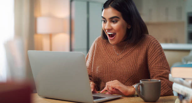 istock Shot of a young woman looking surprised while using a laptop to study at home 1352185960