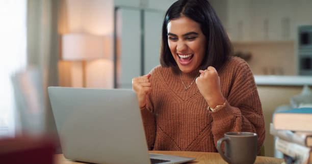 istock Shot of a young woman cheering while using a laptop to study at home 1352185962