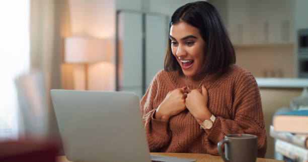 istock Shot of a young woman looking surprised while using a laptop to study at home 1352185966