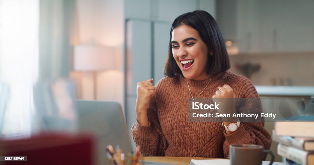 Shot of a young woman cheering while using a laptop to study at home Just got my results... I passed! Celebration Stock Photo