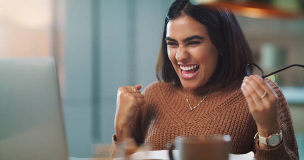 istock Shot of a young woman cheering while using a laptop to study at home 1352185971
