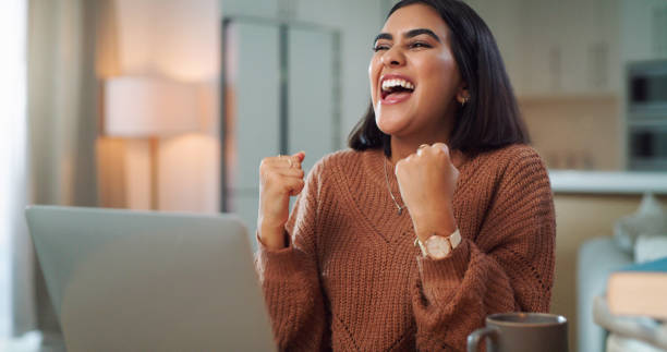 istock Shot of a young woman cheering while using a laptop to study at home 1352185994