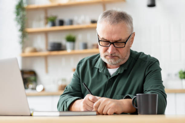 istock Pensive serious elderly man with laptop sitting at table check finances at home 1352187989