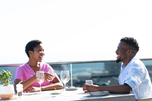 istock Happy young couple sitting at table on roof top deck 1352188969