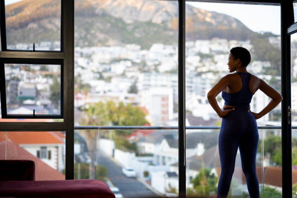 istock Confident woman looking out window while exercising 1352188991