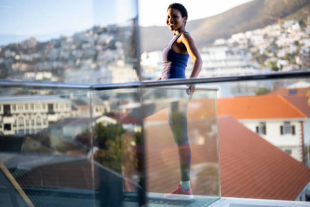 istock Young woman exercises on balcony watching reflection in window 1352189036