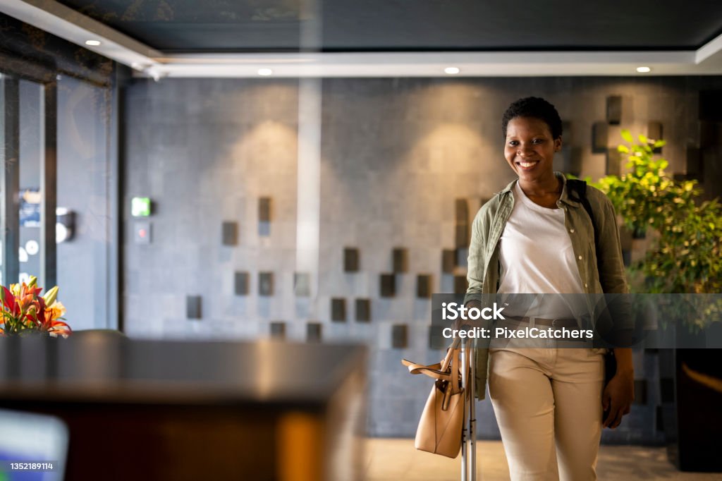 Confident young woman arriving in hotel reception Hotel Stock Photo