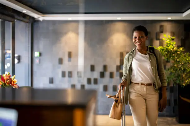 Confident young woman arriving in hotel reception