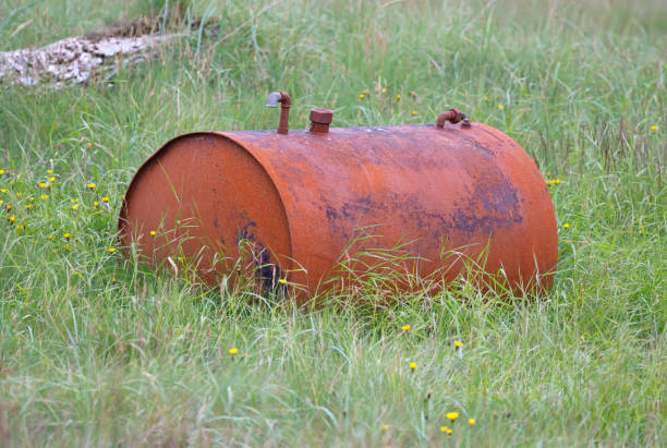 istock Old rusty barrel resting in a field, grass and flowers surround it 1352193502
