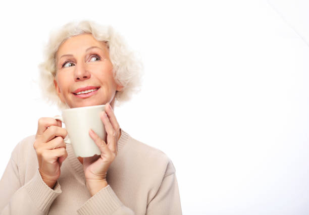 istock old excited lady smiling laughing, holding cup drinking coffee or tea 1352194498