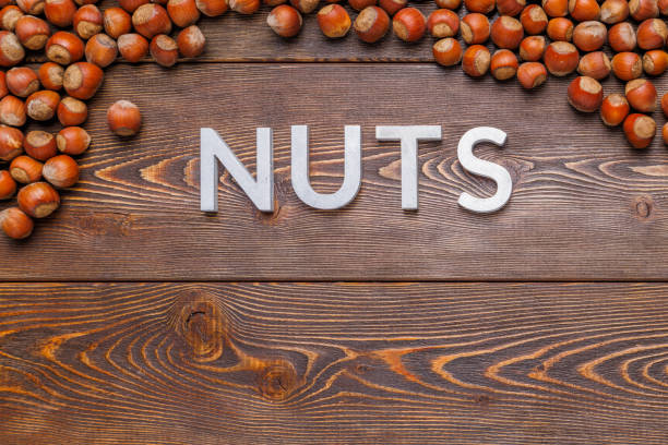 istock the word nuts laid with silver letters on wooden board background surrounded with hazelnuts 1352198293