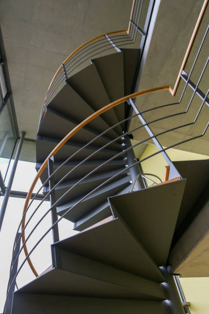 istock Ascending open spiral staircase with handrail in office building 1352200676