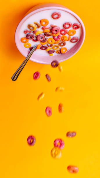 istock Colored cereals falling from a bowl to the ground upside down with the yellow background. 1352200954