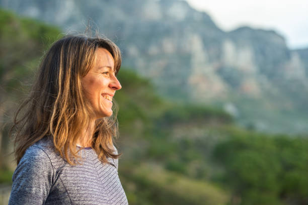 istock Young woman smiling while looking at a scenic view during a hike 1352202020