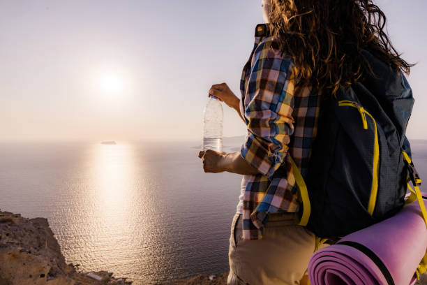 istock Back view of a female backpacker having water break on a hill. 1352204343