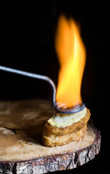 A torrija covered with cream and sugar and flambéed with a hot iron in the traditional style. small flame of fire. typical dessert. selective focus. copy space. text space. french toast.