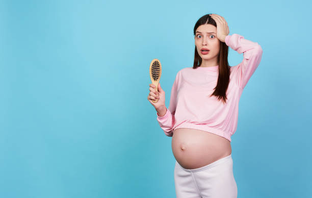 Scared young pregnant girl is losing her hair. stock photo