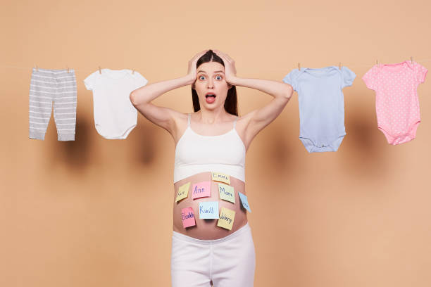 Scared pregnant woman with baby names on her belly. stock photo