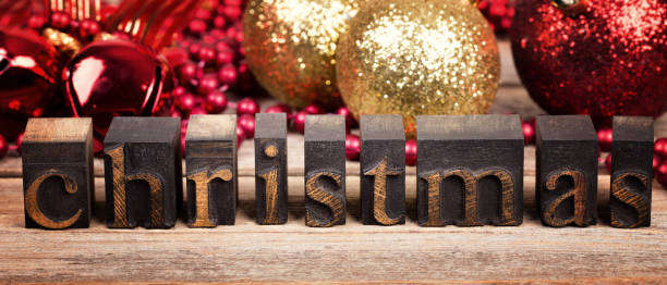 the word christmas written with vintage wood printer blocks. christmas message over old wood with traditional tree decorations behind. - printers ornament imagens e fotografias de stock