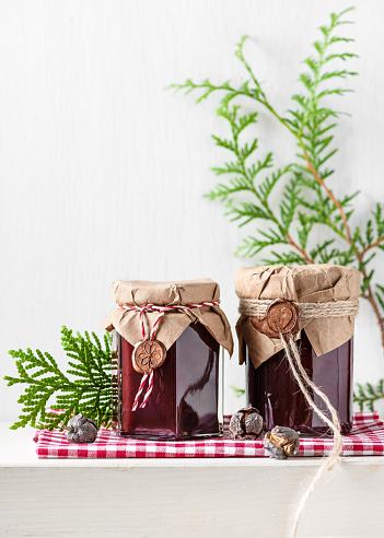 Homemade fruit jam in the glas jars decorated with grunge paper and wax seal as small present for Christmas. Kitchen gift ideas concept. Copy space.