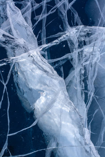 istock A large crack in the ice with small cracks around. Blue transparent ice. 1352208905