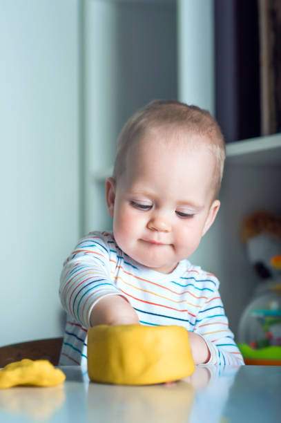 toddler boy playing yellow plasticine play-doh in playroom close-up and copy space.. - playdoh imagens e fotografias de stock