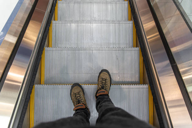 Male feet on an escalator in a shopping center, top view.