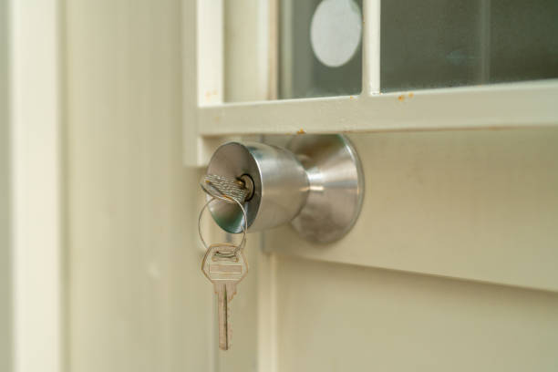 istock Closeup, the key is inserted on the silver doorknob. which is installed on the iron gate with cream color 1352214321